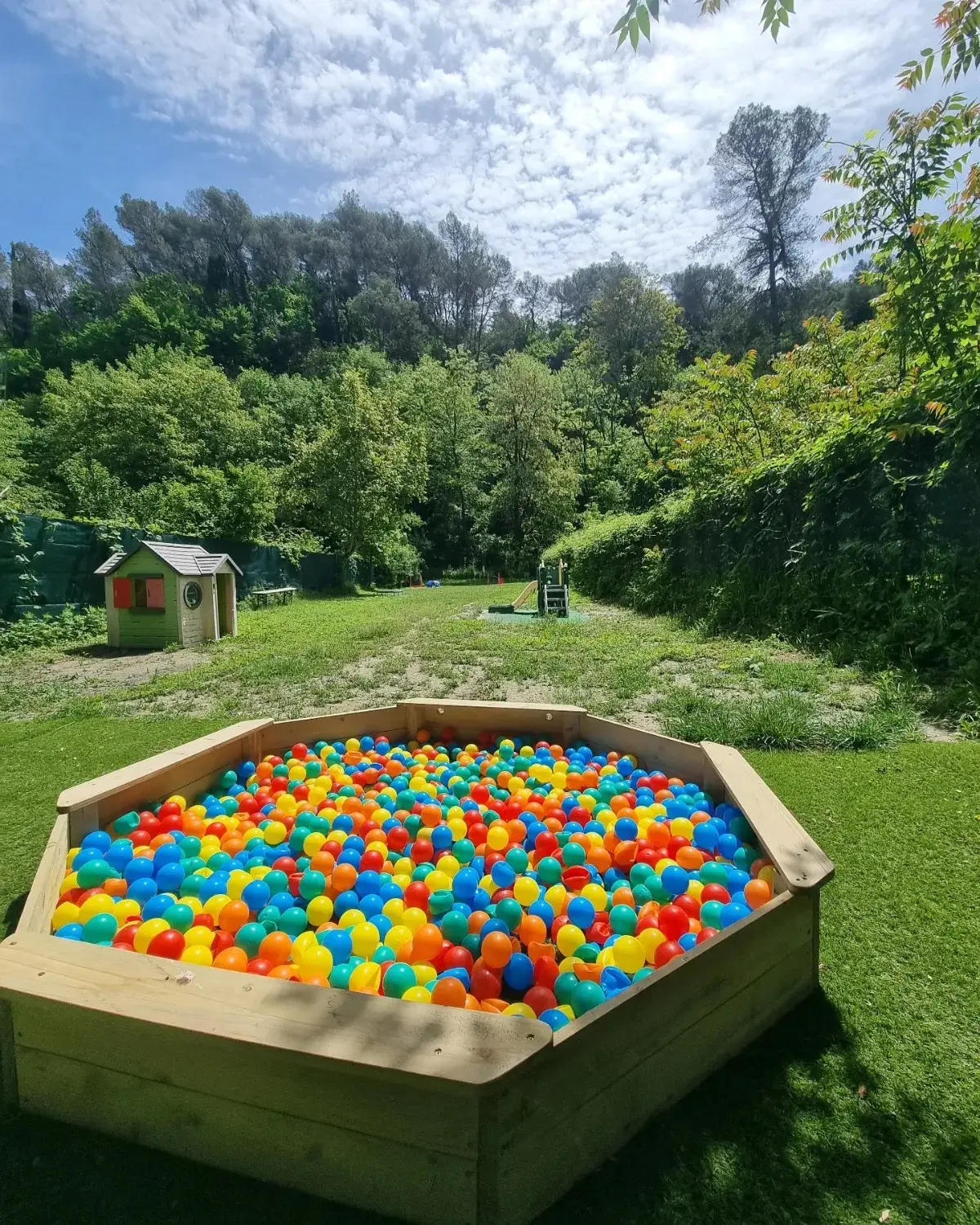 Le terrain sur toute sa longueur : piscine à balles, maisonnette, toboggan, clôture et arbres